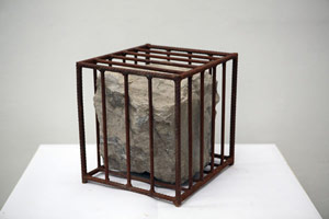 Sui Jianguo / 
Untitled, 1990 / 
Stone and iron cage / 
15.75 x 15.75 x 15.75 in. (40 x 40 x 40 cm) / 
 / 
A body of work that followed the Tiananmen Square pro-democracy protests /  of 1989, the <i>Structure</i> series shifts away from Sui’s earlier figurative /  portraiture to abstract depictions of bondage and healing. The works often /  are comprised of broken boulders joined together with metal nets, chains, /  or staples.