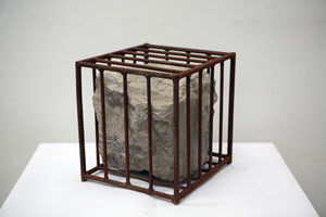 Sui Jianguo / 
Untitled, 1990 / 
Stone and iron cage / 
15.75 x 15.75 x 15.75 in. (40 x 40 x 40 cm) / 
 / 
A body of work that followed the Tiananmen Square pro-democracy protests /  of 1989, the <i>Structure</i> series shifts away from Sui’s earlier figurative /  portraiture to abstract depictions of bondage and healing. The works often /  are comprised of broken boulders joined together with metal nets, chains, /  or staples.