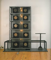 Edward & Nancy Reddin Kienholz / 
The Cage (from The Volksempfängers Series), 1975 / 
box iron, chain-link fencing, galvanized metal, 10 Volksempfänger radios, cloth, one cobblestone tamper, tape player, foot switch, lights, plywood, galvanized sheet metal base / 
75 1/8 x 75 3/4 x 20 in (190.5 x 192.4 x 50.8 cm) / 
Private collection